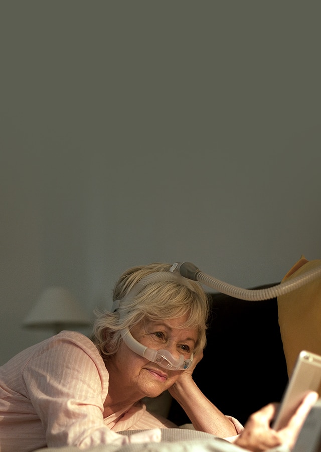 Femme portant le masque ultra-compact nasal AirFit N30i et confortablement installée-mobile