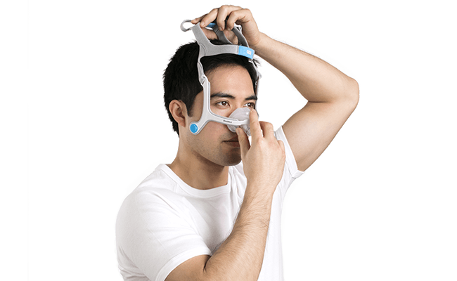 Homme qui met son masque nasal ResMed pour PPC et ventilation