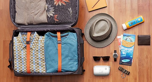 Une valise ouverte soigneusement remplie de vêtements et d’articles essentiels pour voyager, y compris un appareil PPC compact, prêt pour un voyage agréable et adapté à l’apnée du sommeil