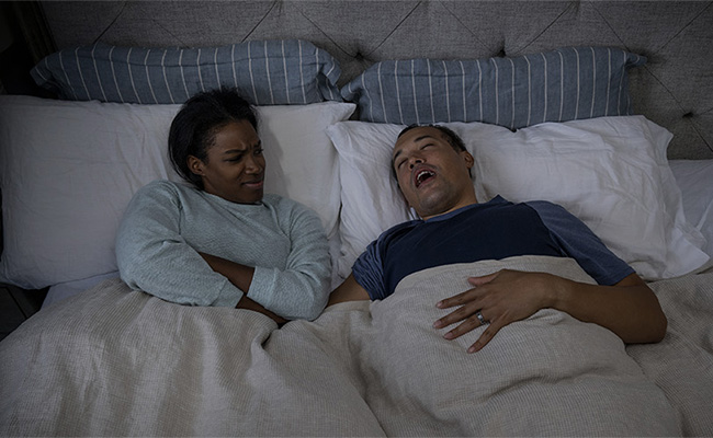 Un homme ronfle au lit et sa femme ne dort pas