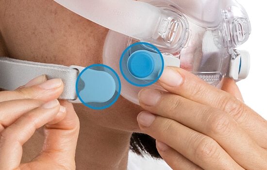 A close-up of the magnetic clips on a ResMed mask being fastened, with the magnets circled